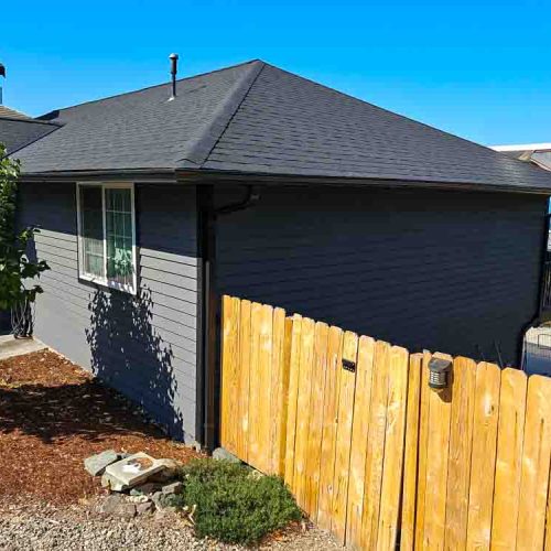 Newly painted wood fences and a house exterior painted gray, and a darker shade for the asphalt roof shingle